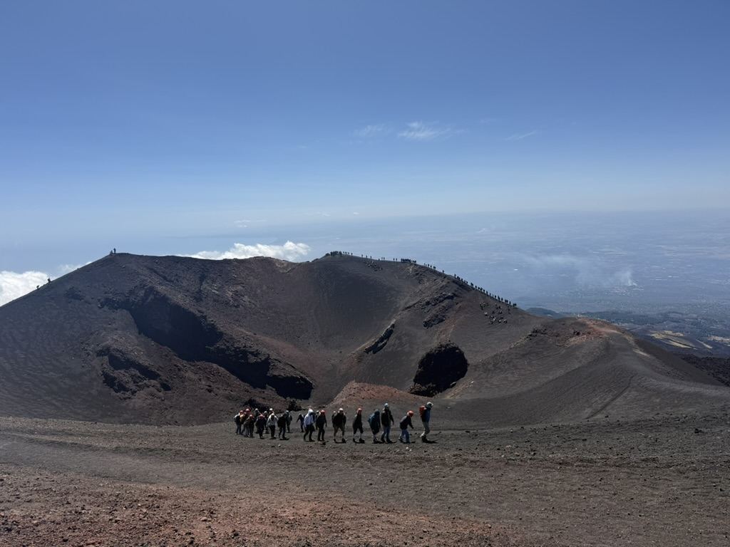 Hikers on the rim of Mount Etna's crater with Sicilian valley below