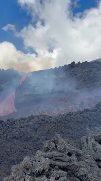 Active lava flow on Mount Etna with steam rising
